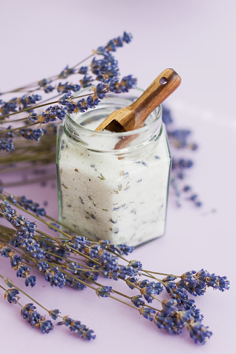Lavender sugar on purple background, close up. Bouquet of dry lavender and glass jar with lavender sugar