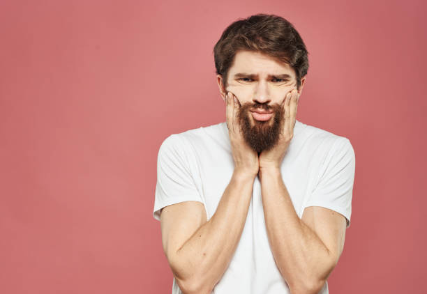istock Guy touches his face with his hands on a pink background cropped view 2149830154