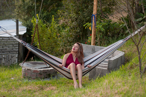 On a serene afternoon, a cozy blonde tourist enjoying
  a hammock in the backyard surrounded by nature