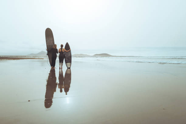 Surfers walking along the beach at Cape Woolamai, Victoria, Australia.