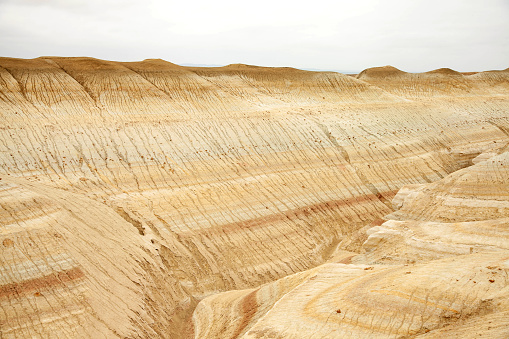 Unique geological feature known as tiger-striped mountains, showcasing layers of sedimentary rock in warm tones that resemble the stripes of a tiger.