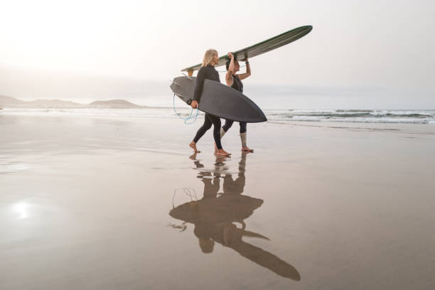 istock Surfer women on the shoreline with surfboards 2149832547