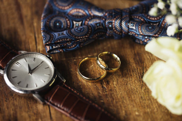istock Golden wedding rings. Rustic wooden table. Buttonhole flowers. Wedding accessories background. Man fashion. 2149833038