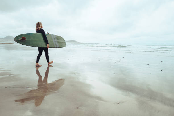 istock Surfer woman on the shoreline with longboard surfboard 2149833161