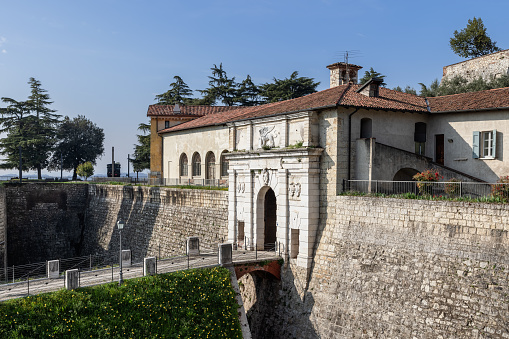 An ancient bas-relief decorates the entrance of Brescia castle, where a stone bridge spans the defensive moat, a testament to Lombardy rich heritage