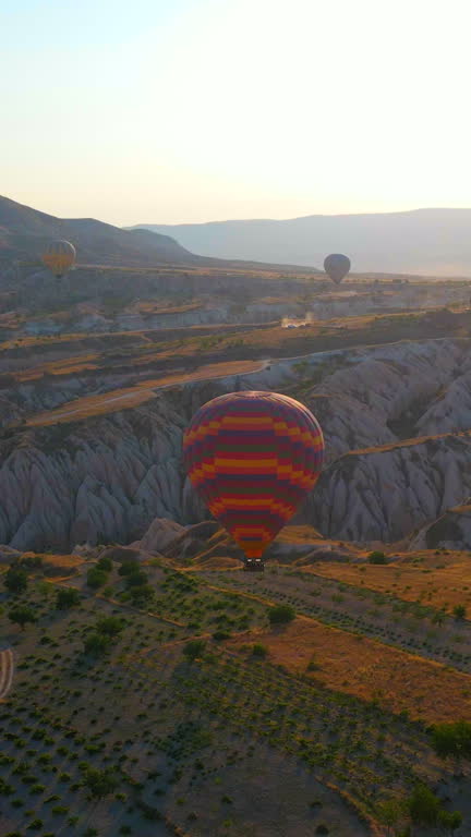 Vertical Aerial video. Captured against the canvas of the Cappadocian sky, this video showcases the enchanting spectacle of a hot air balloon festival. The vibrant balloons rise gracefully over the valleys of Cappadocia, painting a breathtaking scene with
