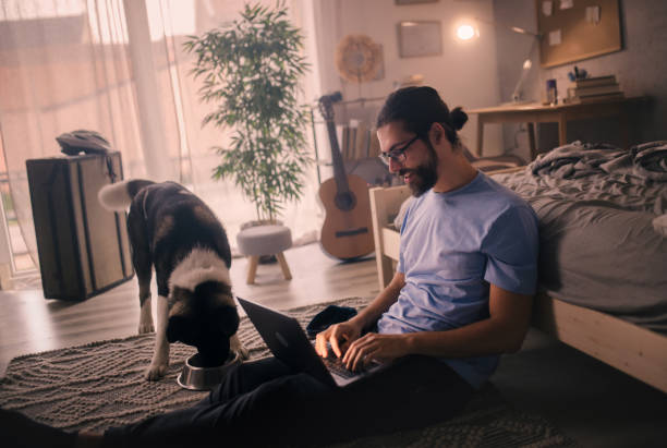 istock young man  using laptop at home .his pet dog is with him 2149837616