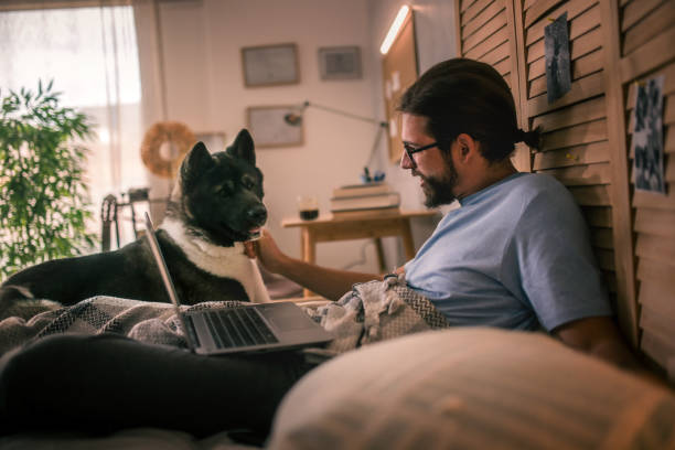 istock young man  using laptop at home .his pet dog is with him 2149837823