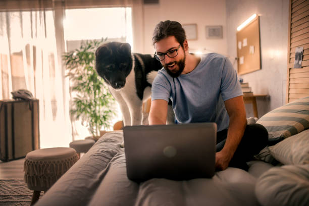 istock young man  using laptop at home .his pet dog is with him 2149837865