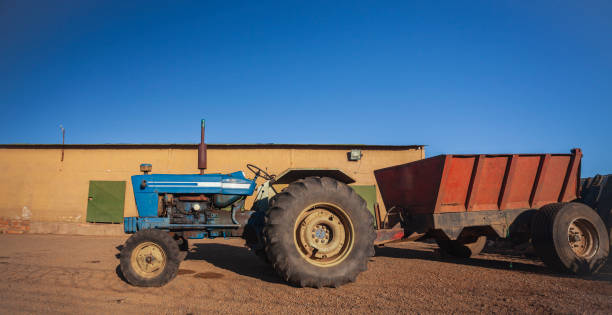 istock An old blue wheeled tractor with trailer stands in rural yard. 2149837883