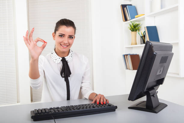 A pretty young professional sitting at her desk and biting her glasses