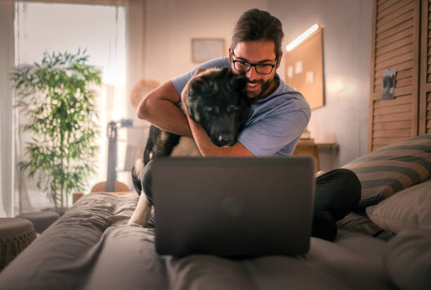 istock young man  using laptop at home .his pet dog is with him 2149837944