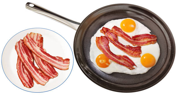 istock Boiled Bacon Slices On Plate And Freshly Fried Crispy Crunchy Gourmet Bacon Rashers With Sunny Side Up Eggs In Large Black Ceramic Coated Frying Pan Isolated On White Background 2149840132