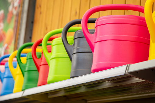 Colorful watering cans are lined up in a row on the shelf