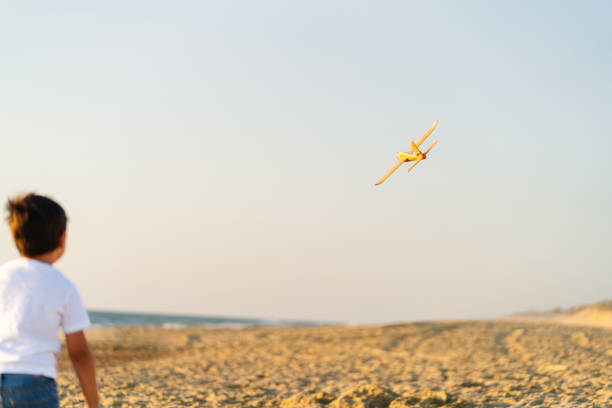 A blurred toy plane in flight above a beach at dusk