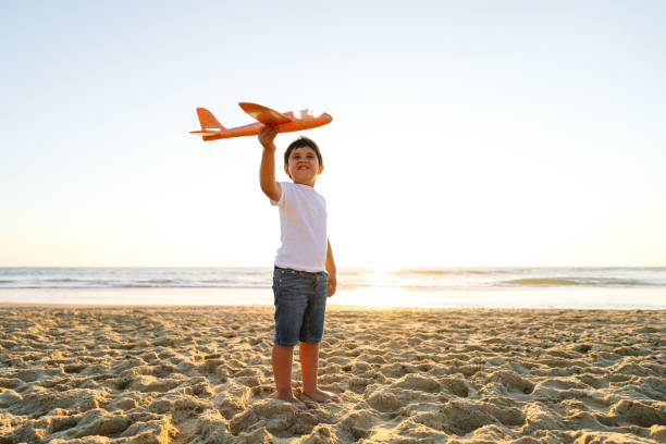 istock Cheerful Boy Holding Toy Airplane on Beach at Sunset 2149840596