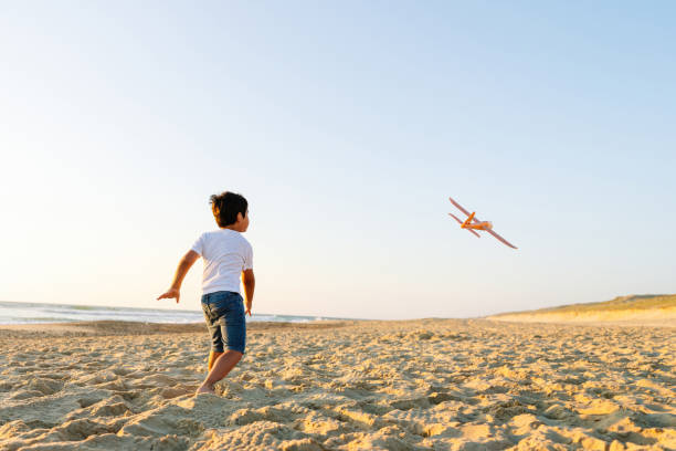 istock Energetic Boy Chasing Flying Toy Plane on Beach at Sunset 2149840638