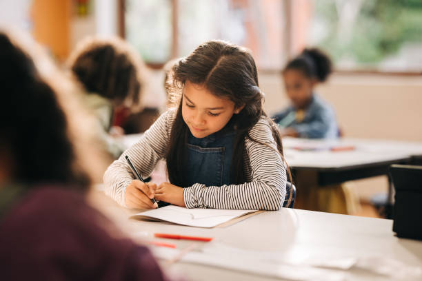 istock Kid writes on a book in a primary school class 2149841161