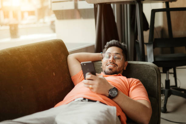 istock Young Man Relaxing on Sofa with Smartphone at Home 2149846911