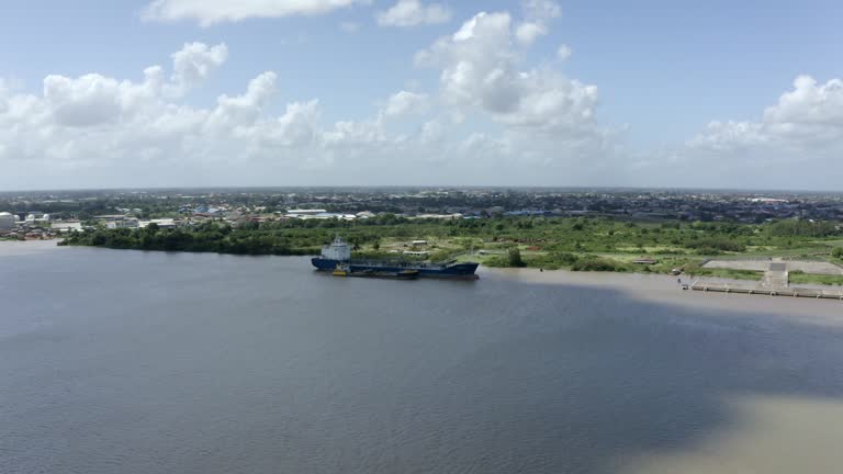 Drone view approaching oil tanker ship in Suriname river, Paramaribo capital of Suriname, cloud shadow over ship
