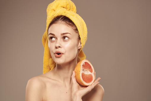 Pretty woman bared shoulders grapefruit in hand natural cosmetics vitamins. High quality photo