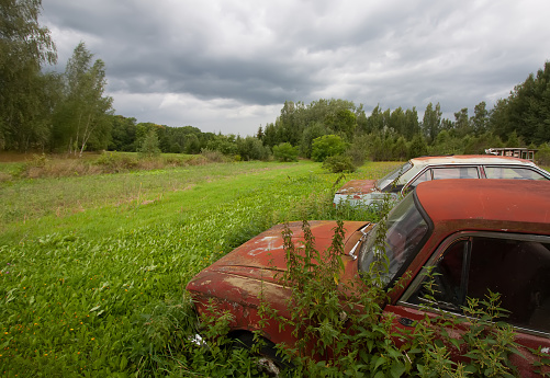 Rusty retro car on the field in a village.
