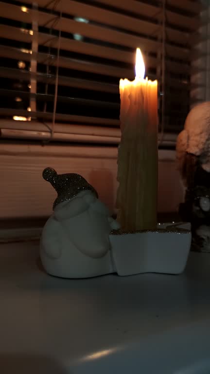 burning wax candle on windowsill at night