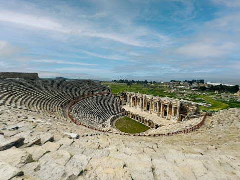 Wide shot of the grand Hierapolis theatre with its ruins overlooking the Pamukkale landscape.