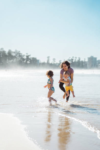 istock Mother plays with young children at the beach 2149856687