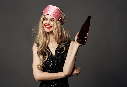 Beautiful blonde with a pink sleep mask and a bottle of beer in her hand. High quality photo