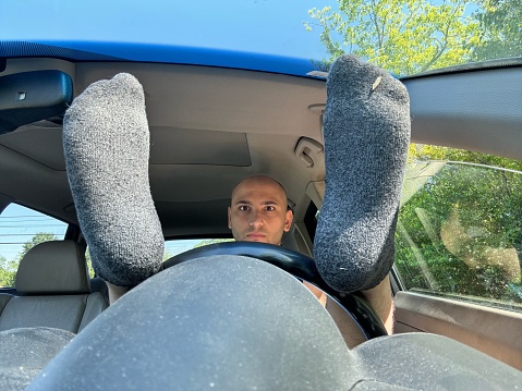23 year old wearing gray socks, feet on steering wheel