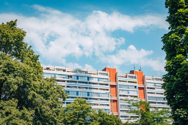 This image showcases a modern apartment complex in Berlin, Germany, seamlessly integrated into a vibrant urban green space. The clear sky and lush trees enhance the clean, architectural lines.