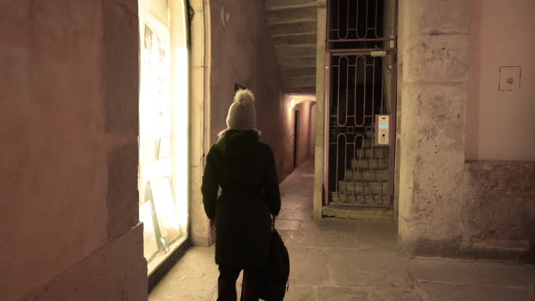 Lyon, France, December 27, 2023. Fascinating night footage of one of Lyon's traboules: the characteristic covered pedestrian walkways. A middle-aged woman walks along it.