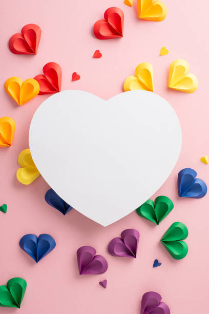 istock Colorful vertical paper hearts in rainbow colors form an inspiring pattern around a blank white heart on a soft pink background, perfect for messages of love and unity 2149858818