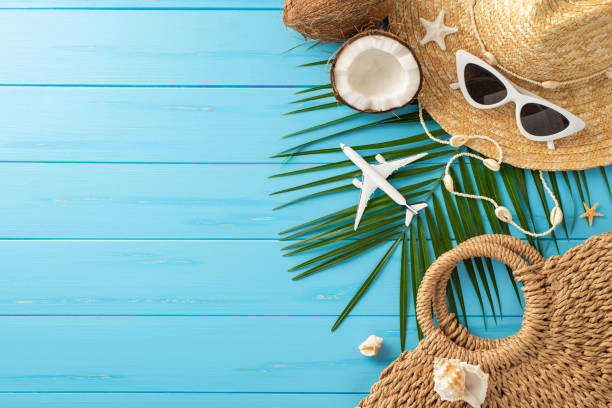 istock A vibrant summer holiday setup featuring a straw hat, sunglasses, coconut, palm leaf, beach bag, and decorative seashells on a vivid blue wooden background, evoking a beach getaway vibe 2149858833