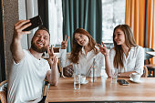 Three Friends Showing A Peace Sign During Coffee Time Selfie