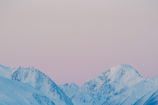 Pink colored mountains by the morning light at the Altai mountains. Sunrise reflection on a snow mountains. Mountain peaks with morning light. Copy space.