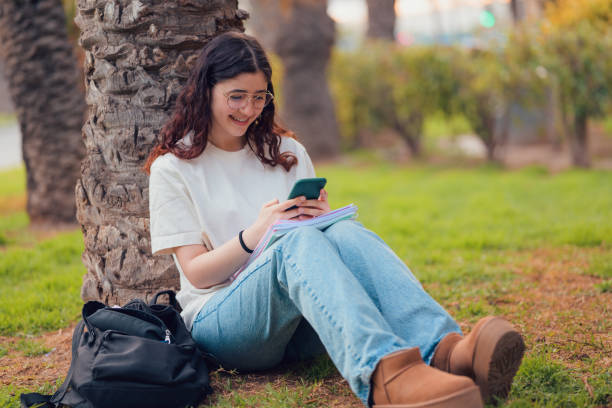 istock Woman sitting on ground using cell phone 2149860747