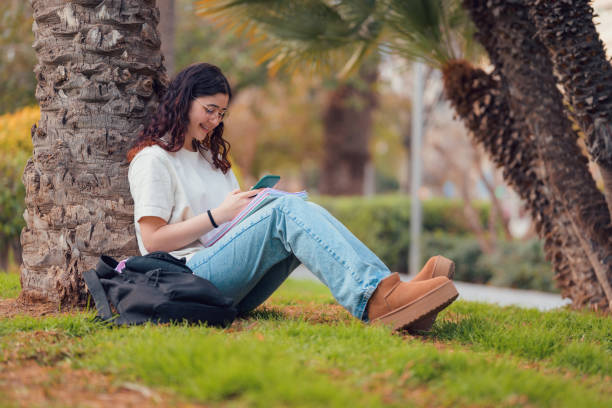 istock Woman sitting on ground using cell phone 2149860751