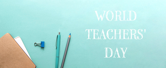 A blue and green background with a pencil and pen on it. world teachers day celebration concept