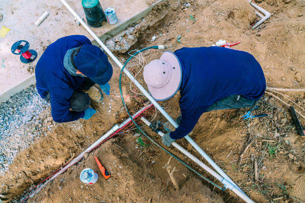 Two Workers Together Digging in Dirt to Install PVC Sprinkler System