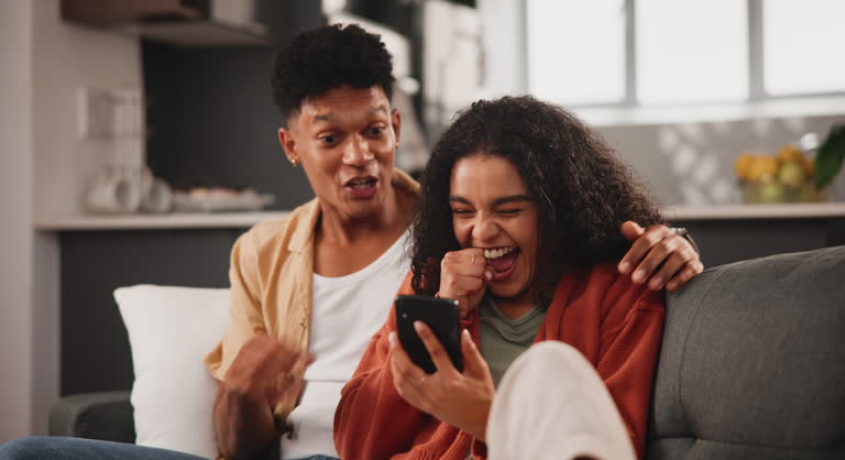 Home, relax and couple with a cellphone, surprise and love with relationship, lotto and excited in a lounge. Apartment, man or woman with smartphone and prize with competition giveaway or digital app
