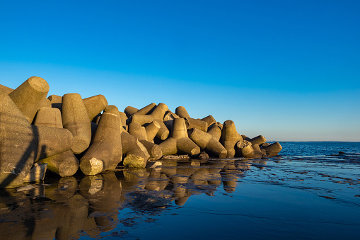 Japan. Fujisawa Island. Kanagawa Prefecture. Breakwater of stone fragments. Water, shore and barrier of stones. Seascape. Stone blocks of unusual shape on the shore.