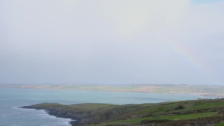 Weather in the coastal Ireland with rain, sun and rainbow. Misty conditions, overlooking ocean