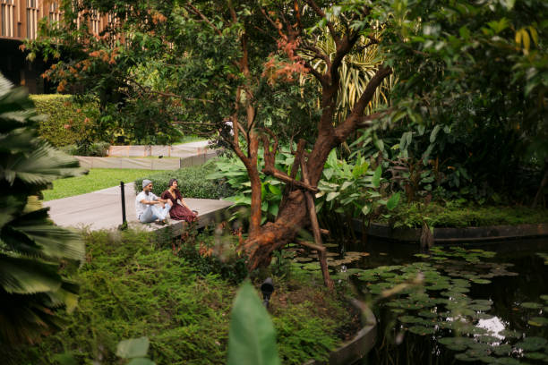 High angle view of young couple talking while relaxing by the pond in the park. Couple in love spending leisure time together at city park, sitting along the pond.