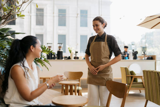 istock Waitress assisting with female customer sitting in cafe 2149873092