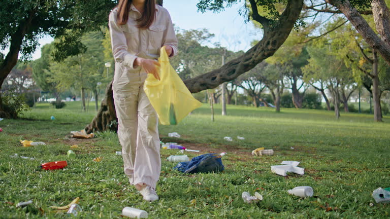 Girl participate park cleanup holding yellow bag. Woman collecting trash nature