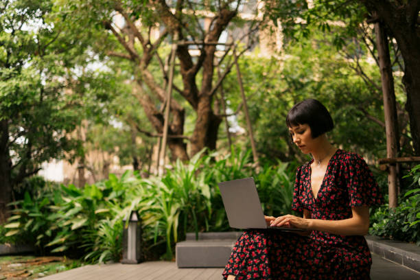 istock Young woman surfing the internet on a laptop while sitting at park 2149876729