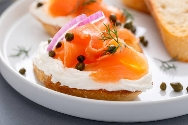 Making salmon crostini or bruschetta with smoked salmon, cream cheese and capers