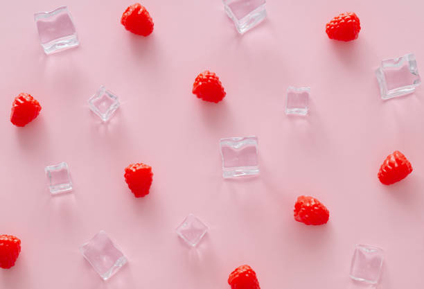 istock Creative summer pattern made of raspberries and ice cubes on light pink background. Fruit minimal concept. Trendy healthy food pattern background idea. Flat lay. 2149878800